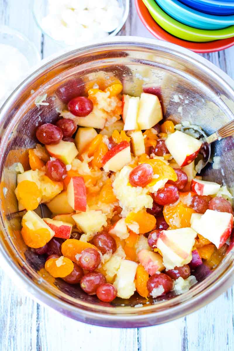 Bowl of fruit being mixed together to make this easy marshmallow fruit salad