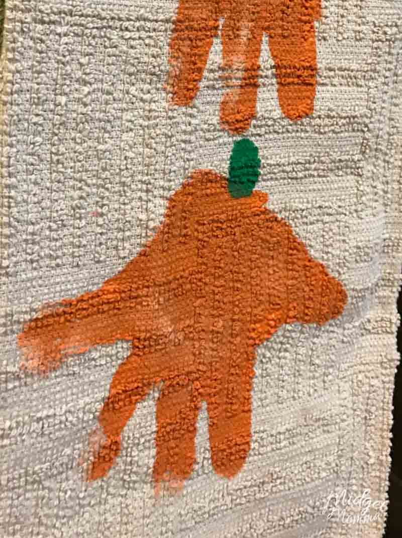 kids handprint in orange paint with green stem to make a pumpkin