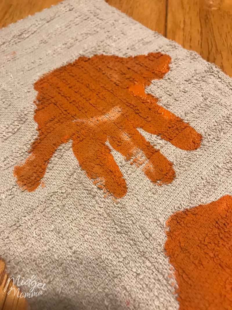 kids hand print in orange paint on a tan towel