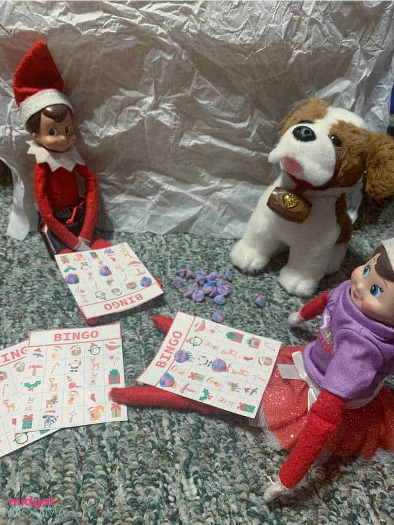 Elf on the shelf playing elf sized bingo with stuffed animals. 