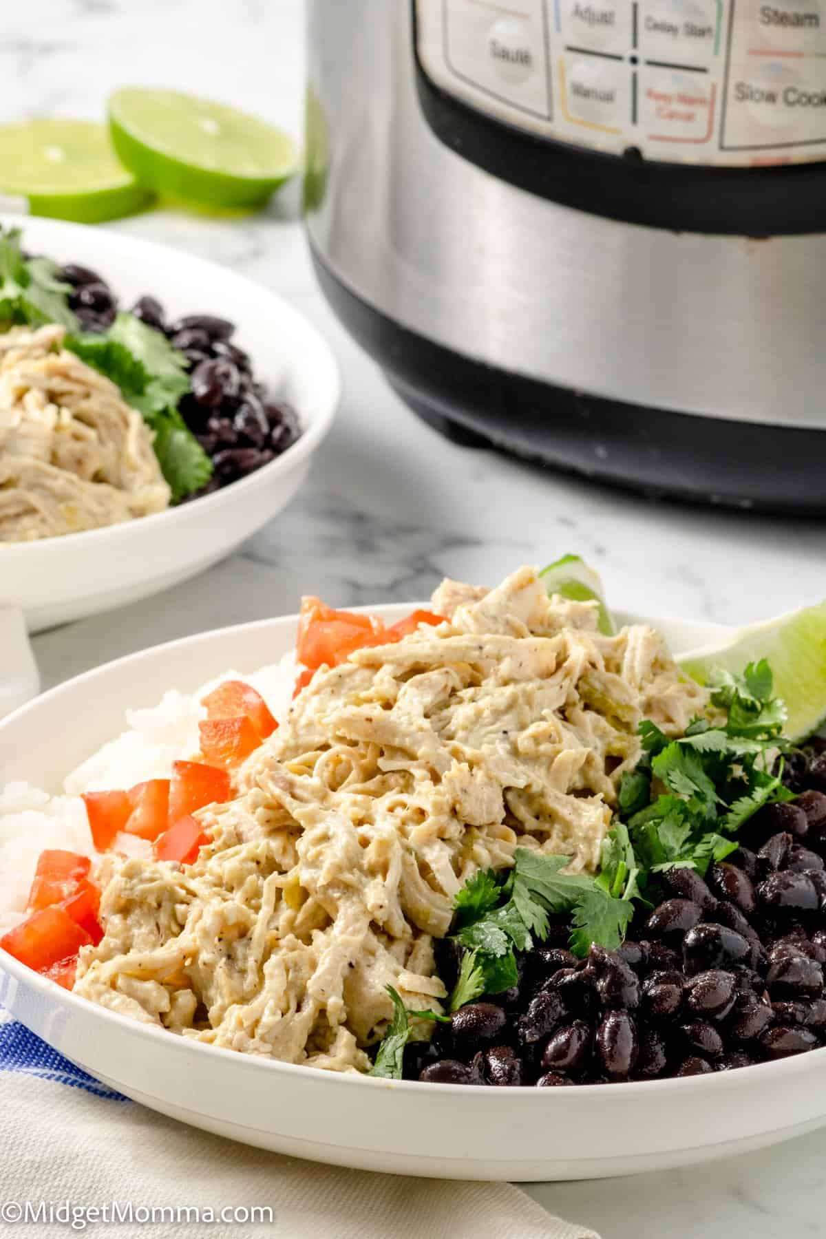 Instant Pot Green Chile Chicken in a bowl of rice topped with black beans, tomatoes, lime and cilantro