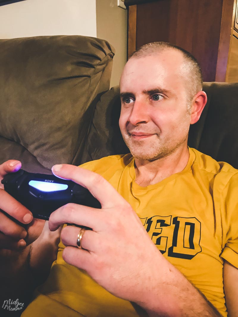 A man on a couch playing Sony Playstation.