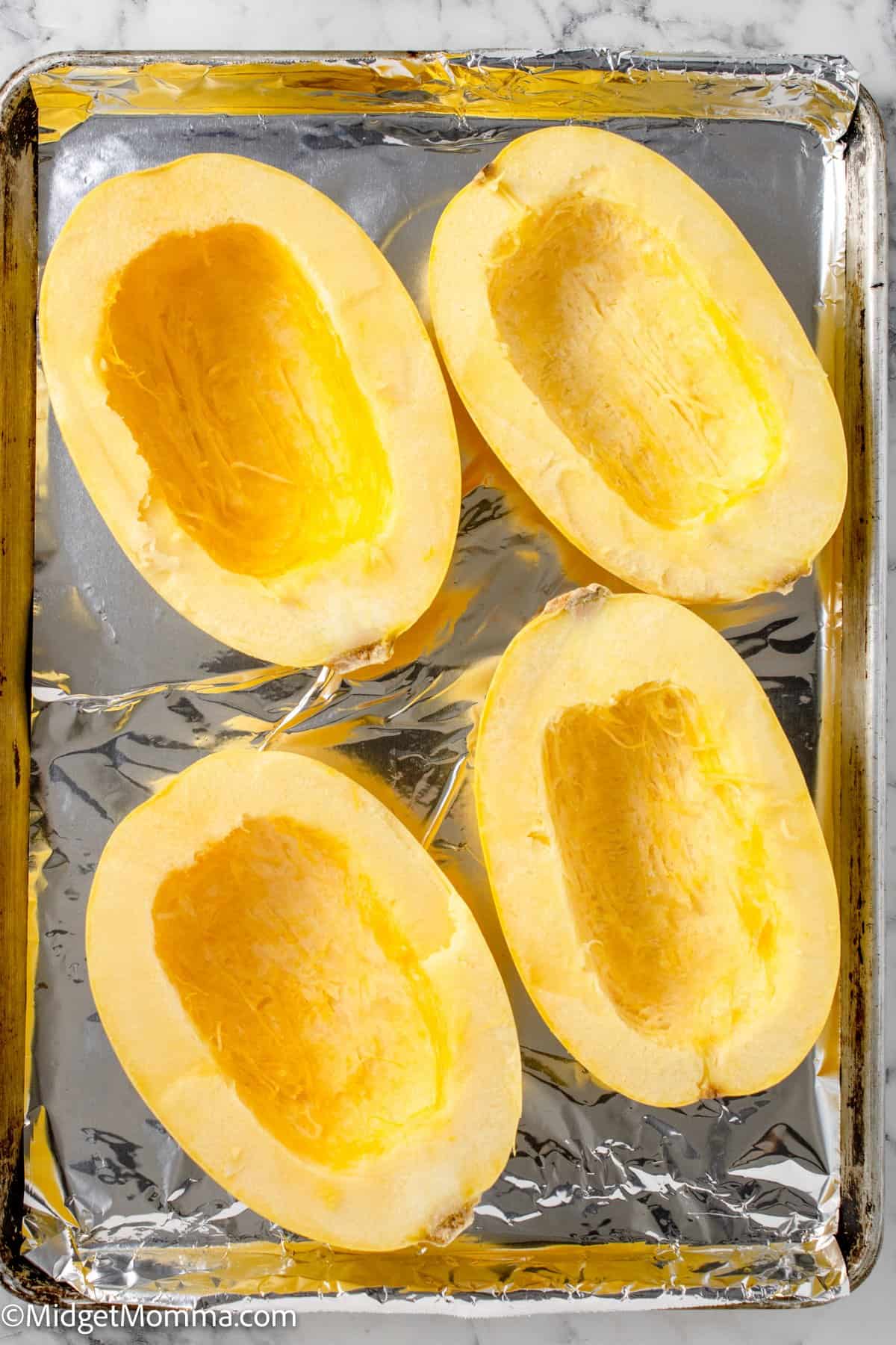 open spaghetti squash on a baking sheet lined with tinfoil