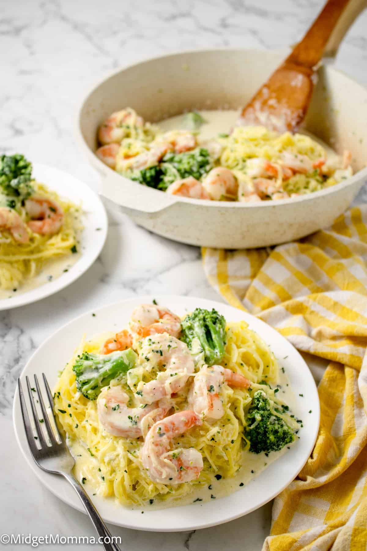 white plate with Shrimp Alfredo Spaghetti Squash with Broccoli and the serving dish with the rest of the meal in the background 