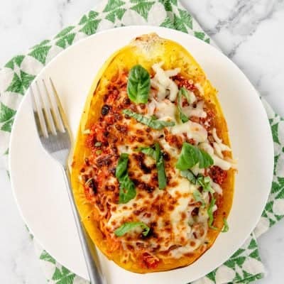 baked lasagna spaghetti squash on a white plate with a fork next to it