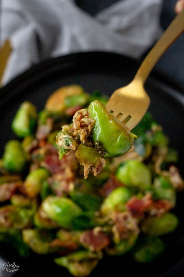 Brussel sprouts with bacon side dish recipe on a black plate, with a fork full of cheesy brussel sprouts