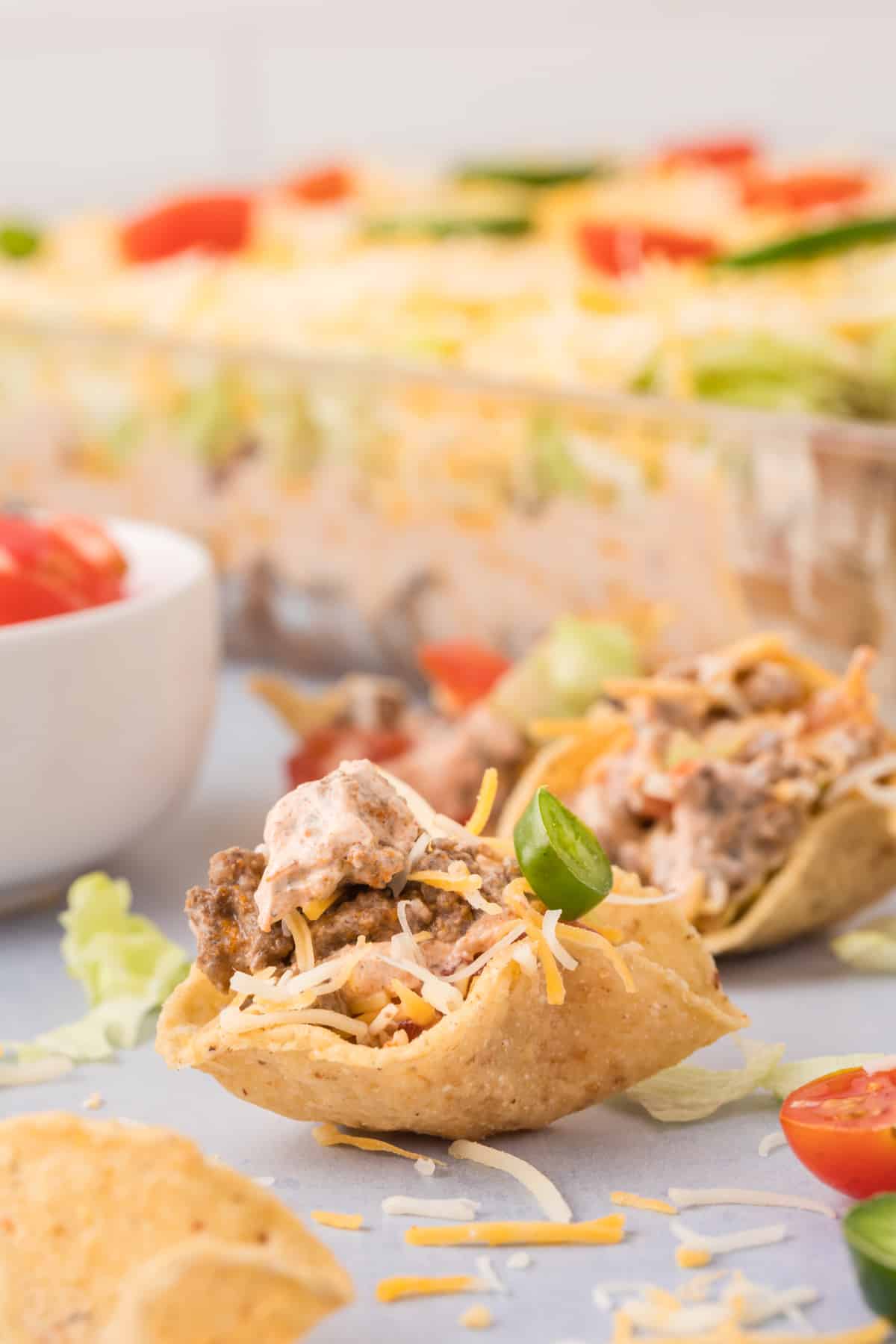 A dish of taco dip with tortilla chips and tomatoes.