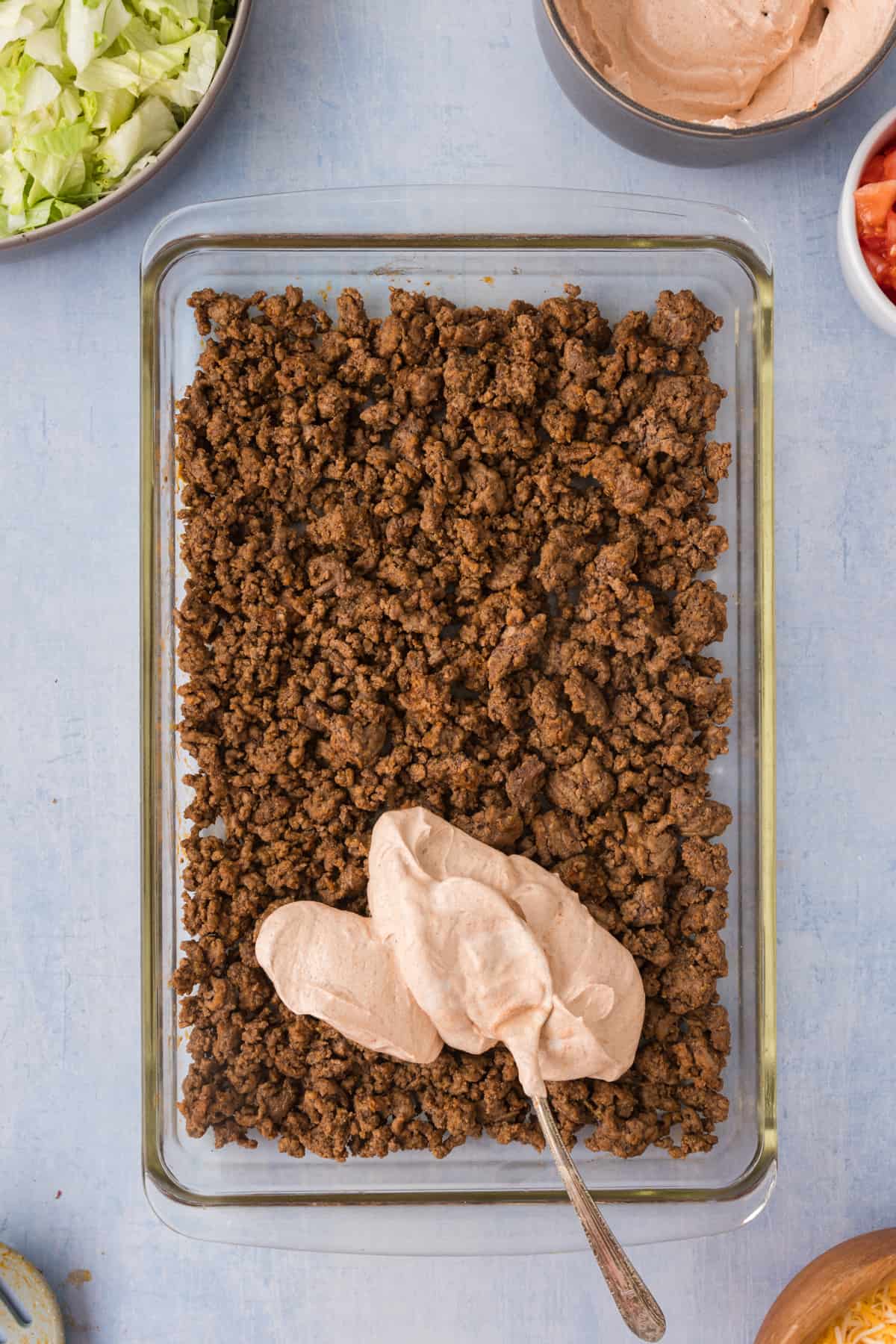 A casserole dish filled with taco meat, and sour cream.
