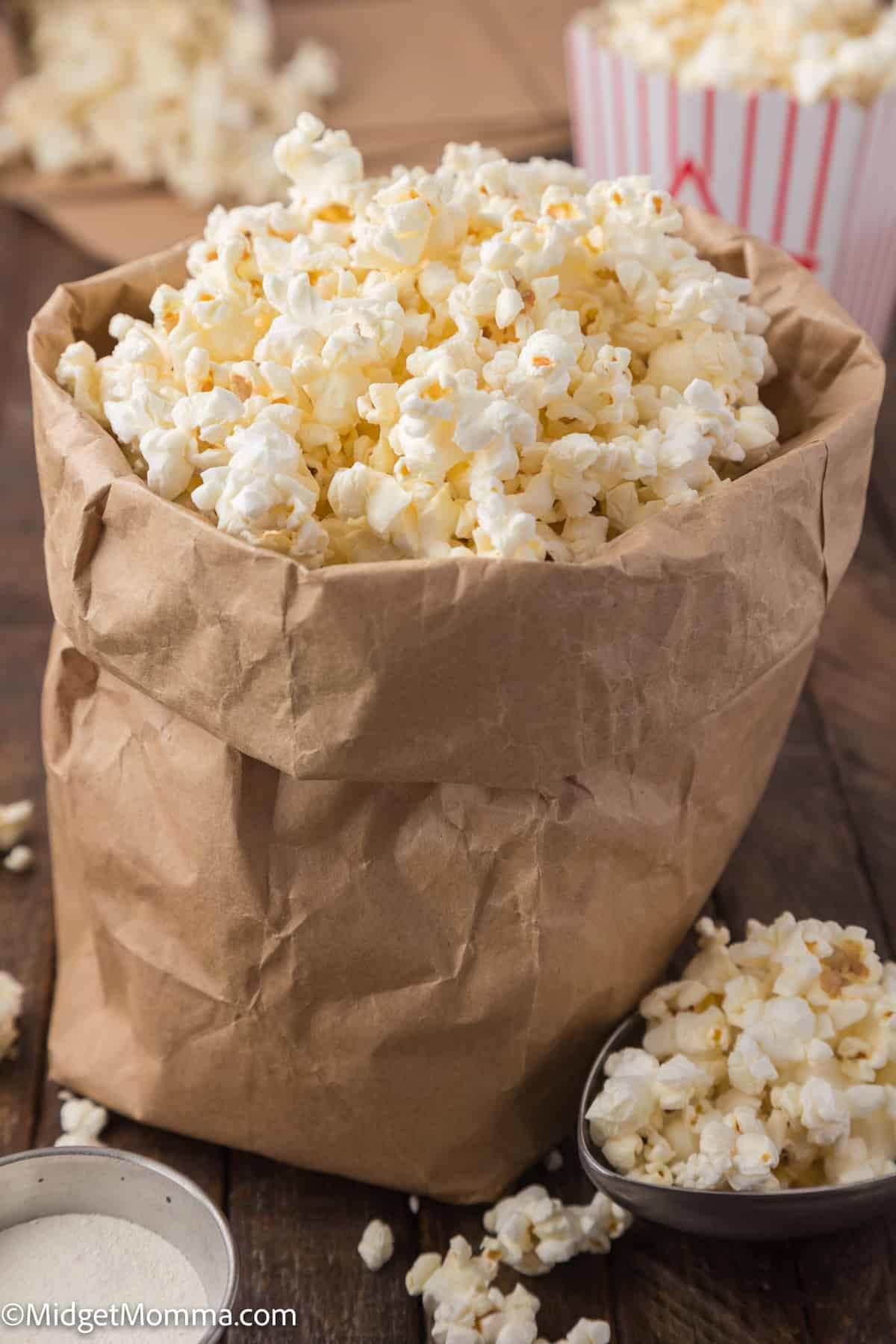 A bag of popcorn with some popcorn kernels spilled on the wooden surface.