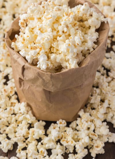 A brown paper bag filled with freshly popped popcorn spilling out onto a wooden surface.