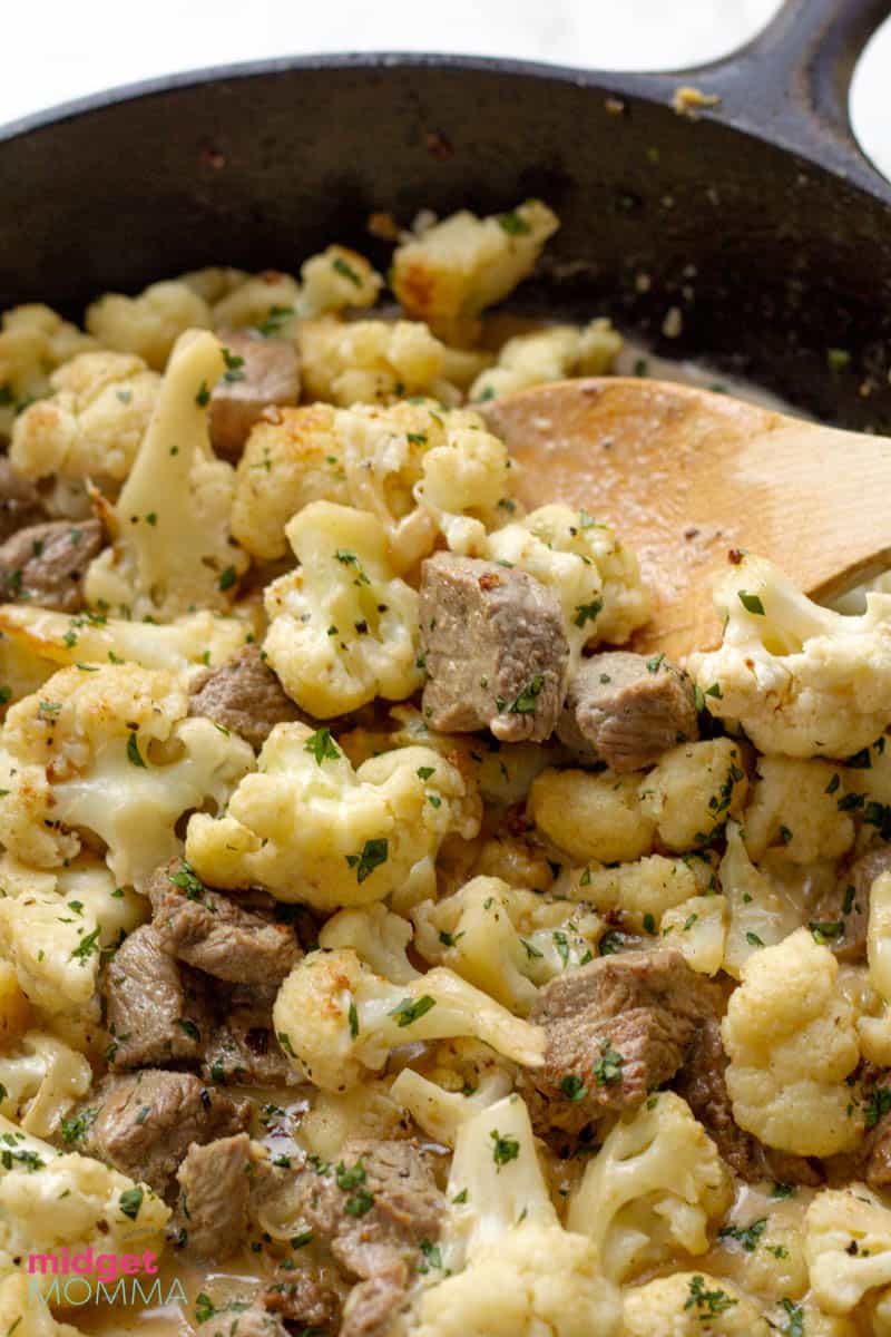 close up photo of cauliflower and steak in a pan