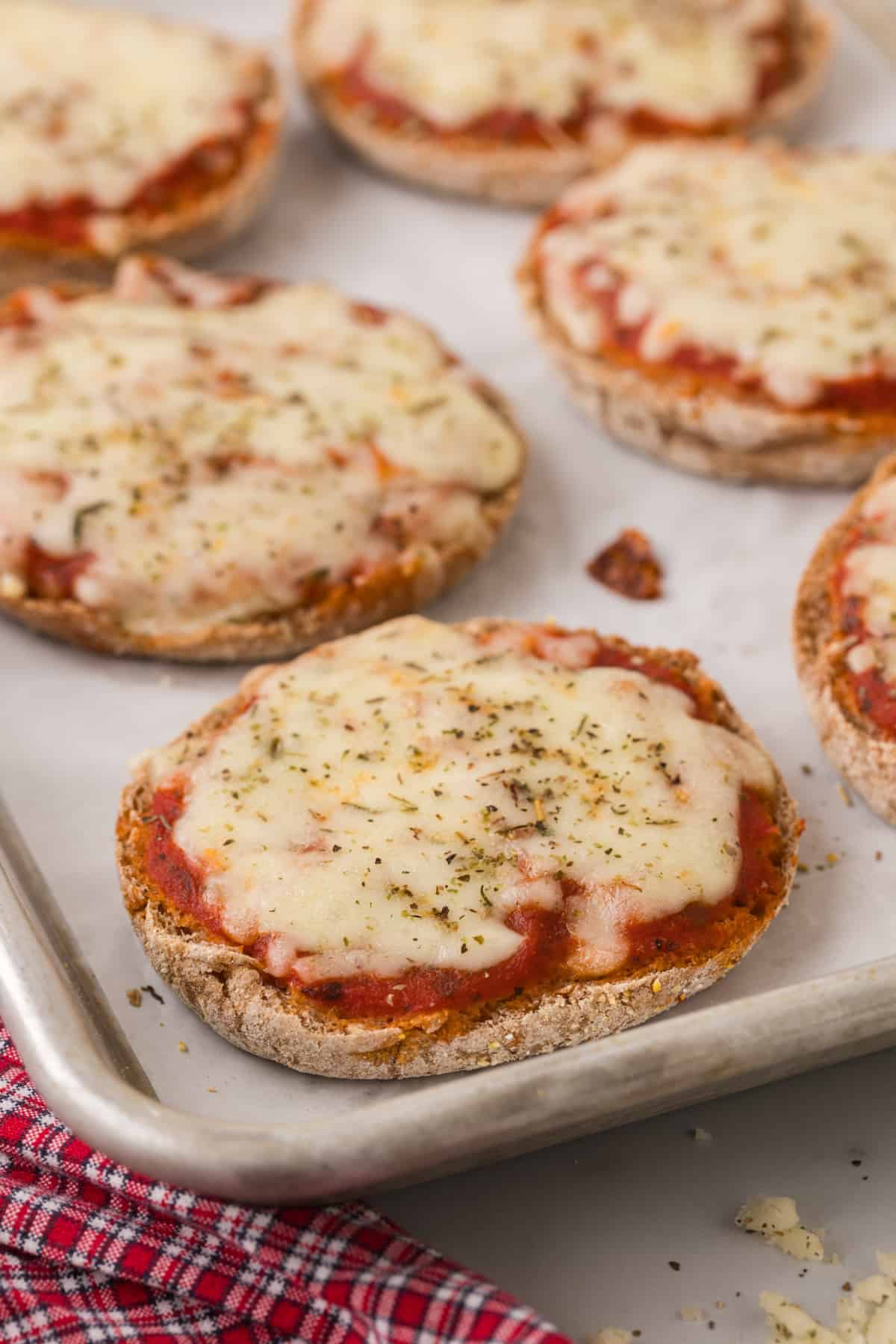 A baking sheet with cooked mini pizzas on it.