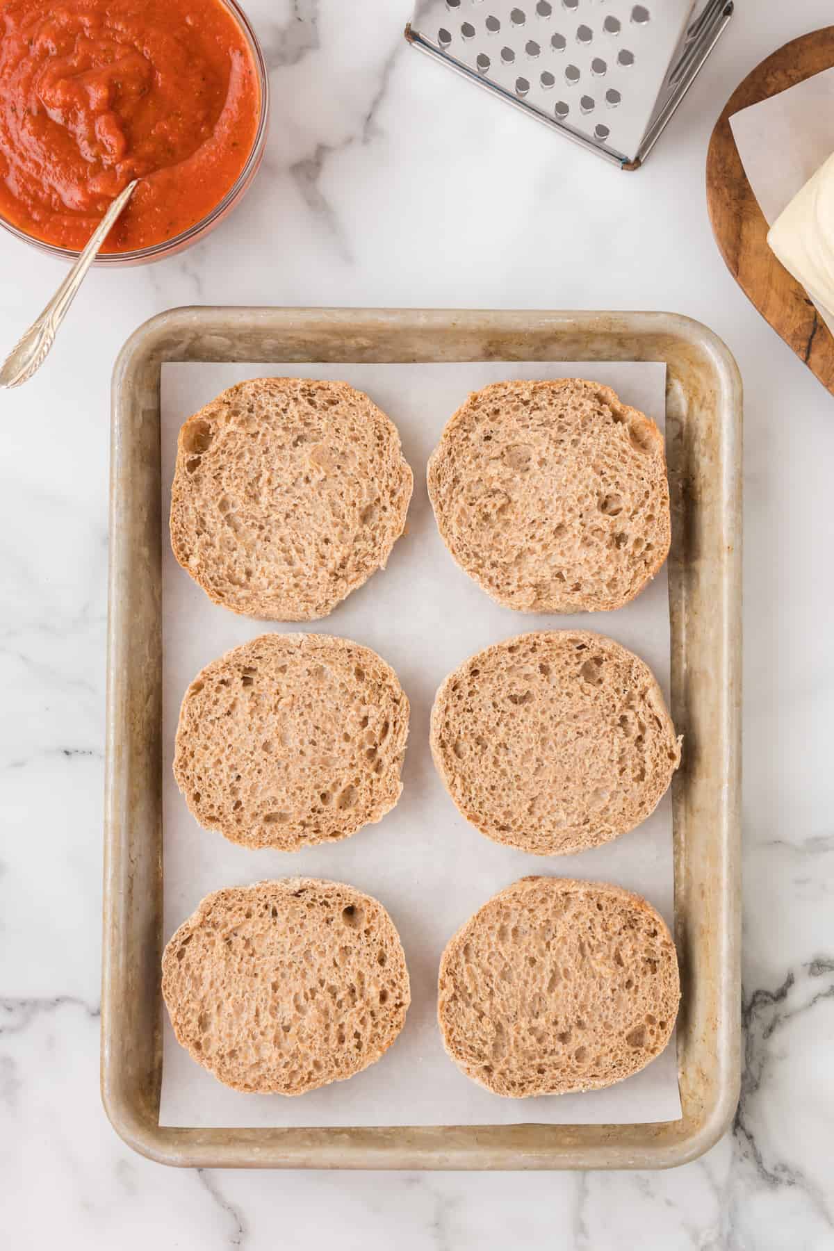 english muffin halves on a baking sheet.