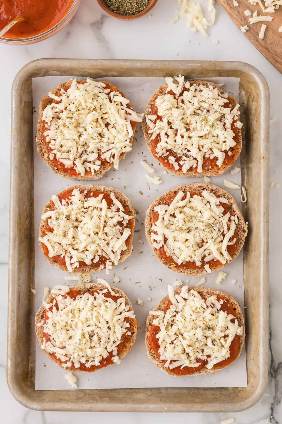 english muffin halves on a baking sheet ready to be baked in the oven