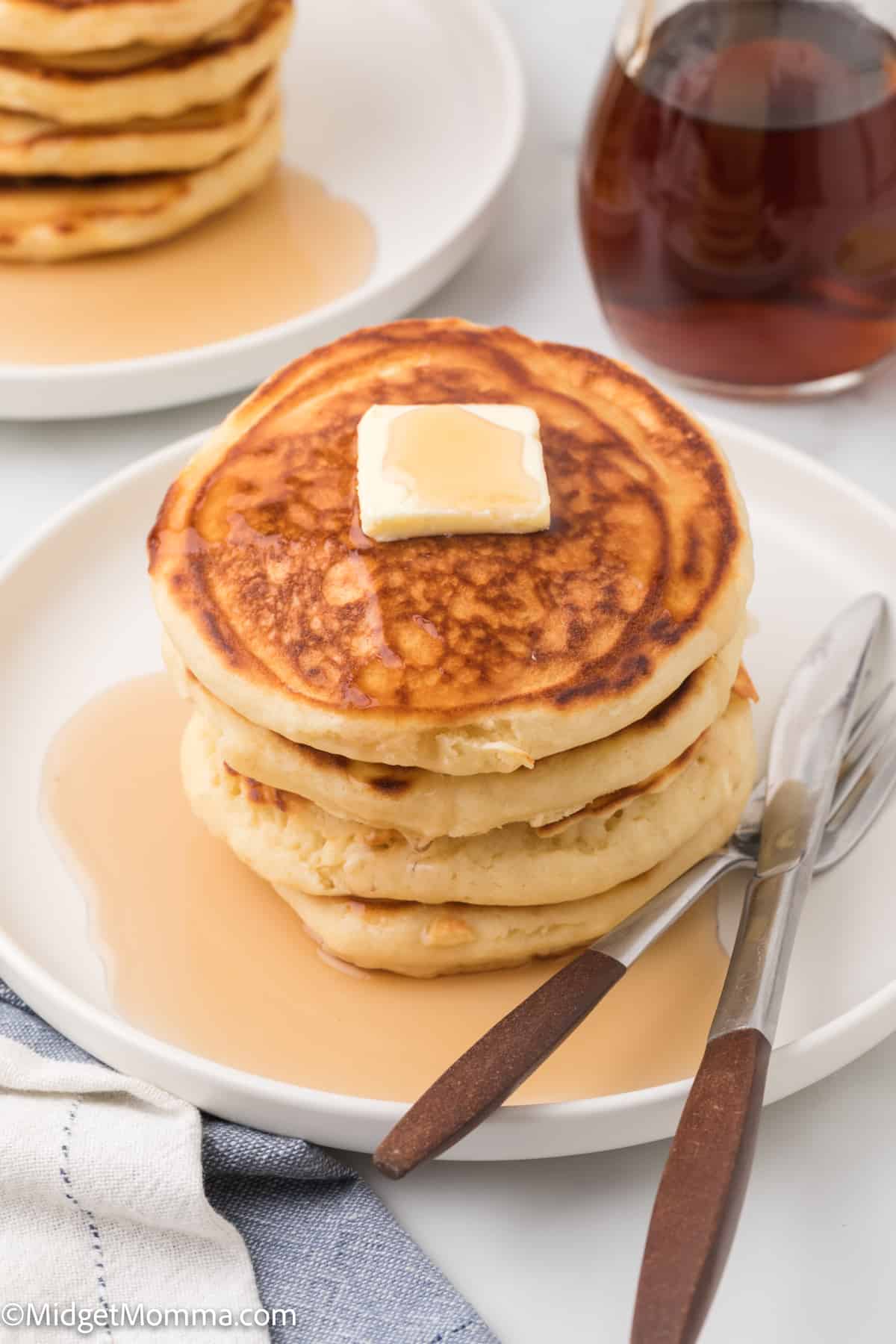 stack of The Best Fluffy Homemade Pancakes on a plate topped with butter and maple syrup