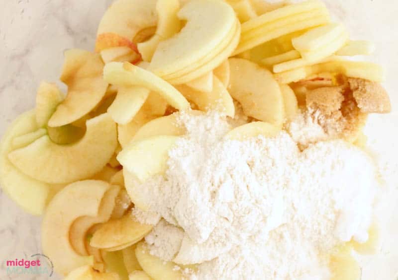 peeled and sliced apples in a bowl tossed with sugar