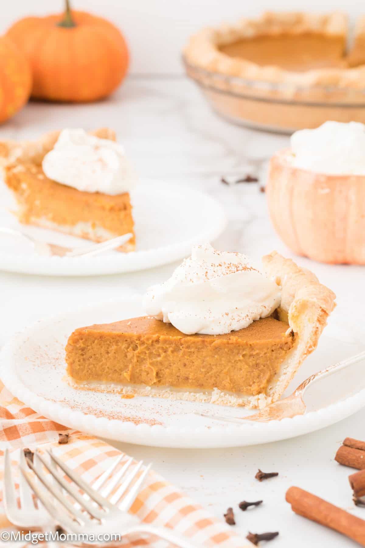 piece of pumpkin pie from scratch on a while plate topped with homemade whipped cream