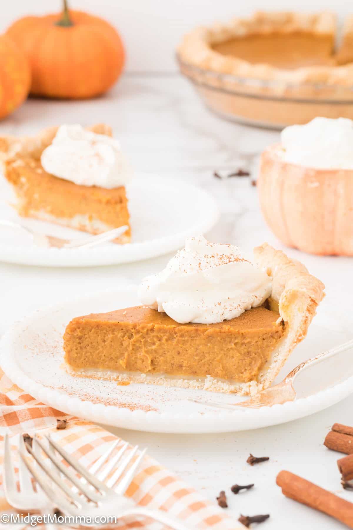 piece of pumpkin pie from scratch on a while plate topped with homemade whipped cream