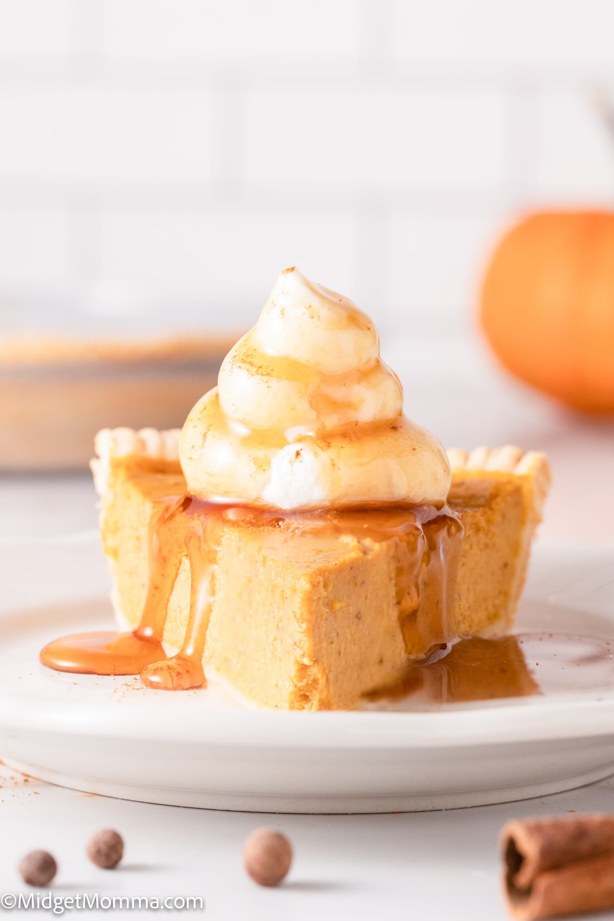 Slice of Maple Pumpkin Pie on a plate drizzled with maple syrup and topped with whipped cream