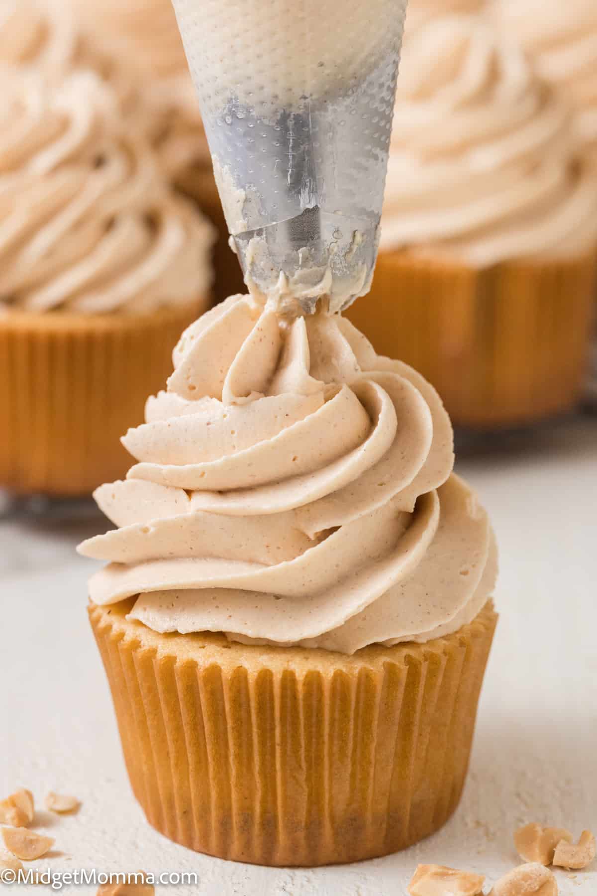 Peanut butter buttercream frosting being piped onto a cupcake