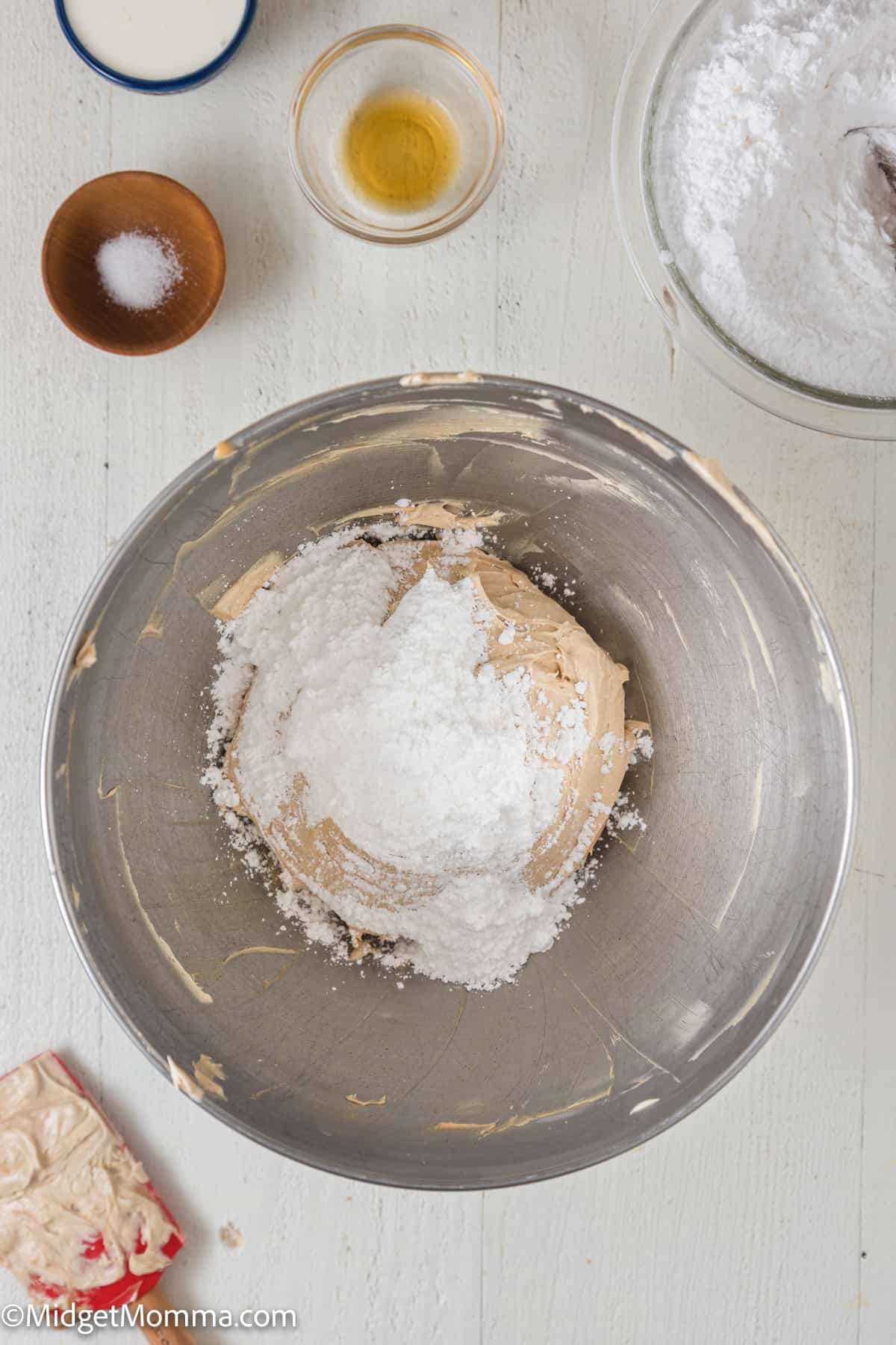 powdered sugar being added to the mixture in the bowl of a stand mixer