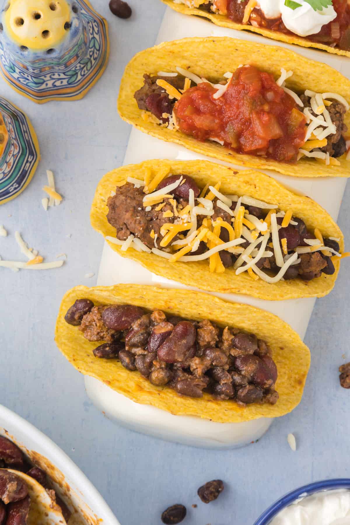 A crock pot full of meat and beans with a wooden spoon.