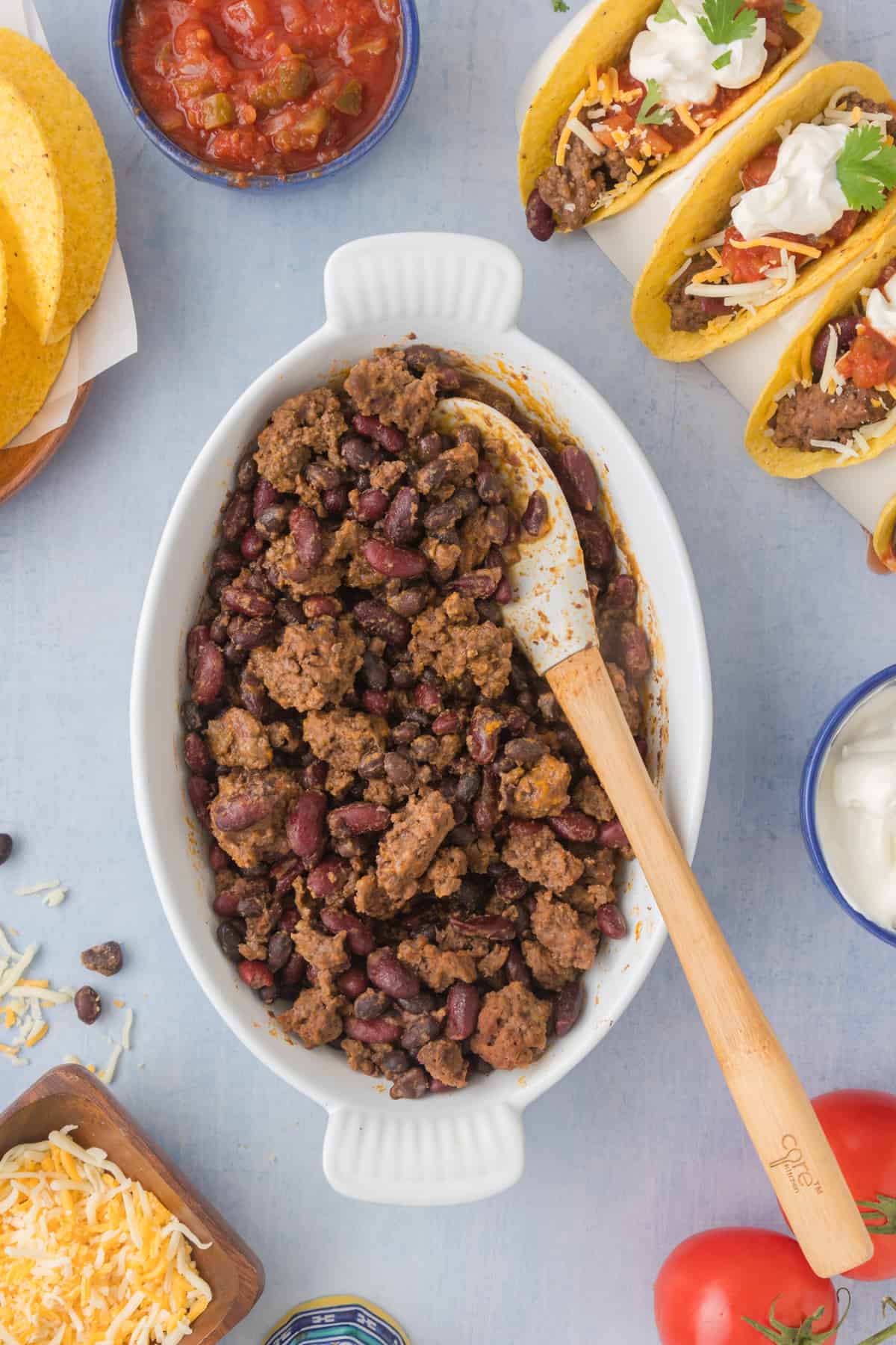 A bowl of slow cooker taco meat with beans, tomatoes and tortillas.