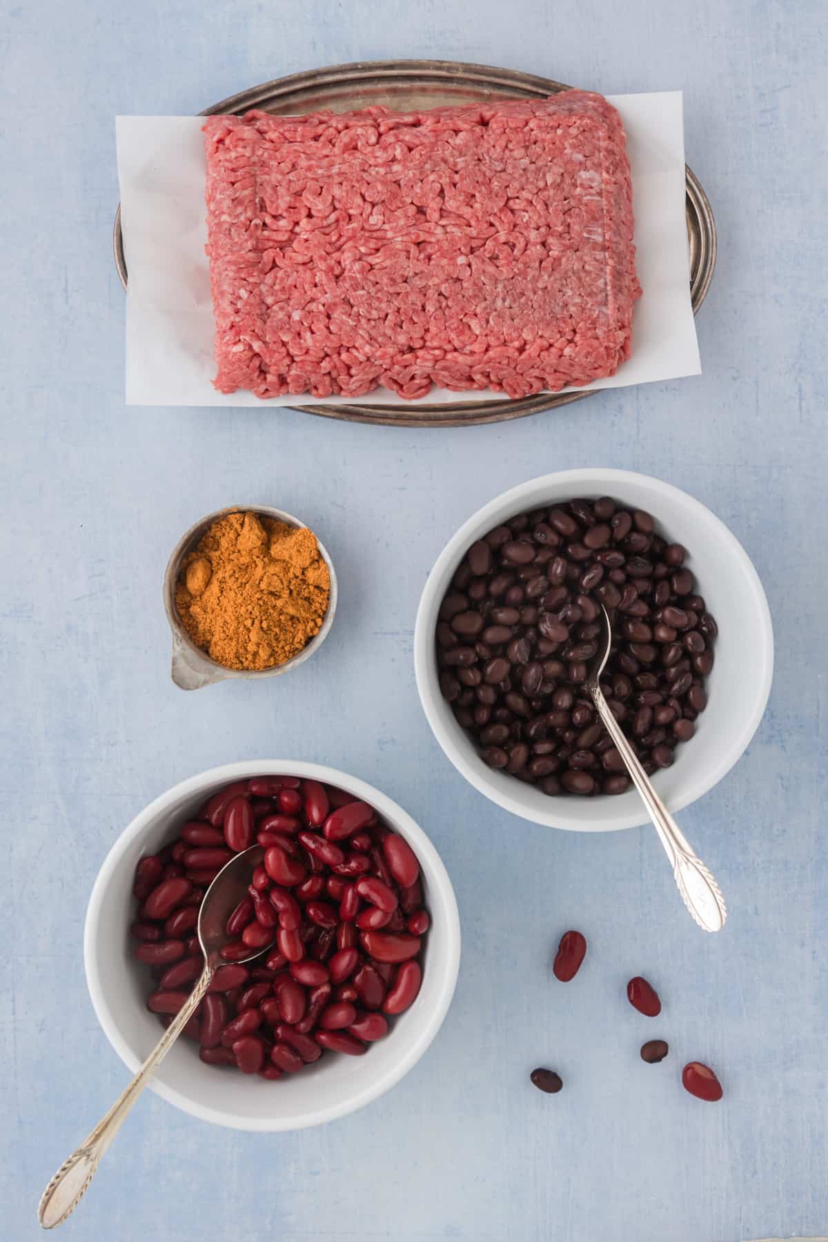 A bowl of meat, beans and spices on a blue background.