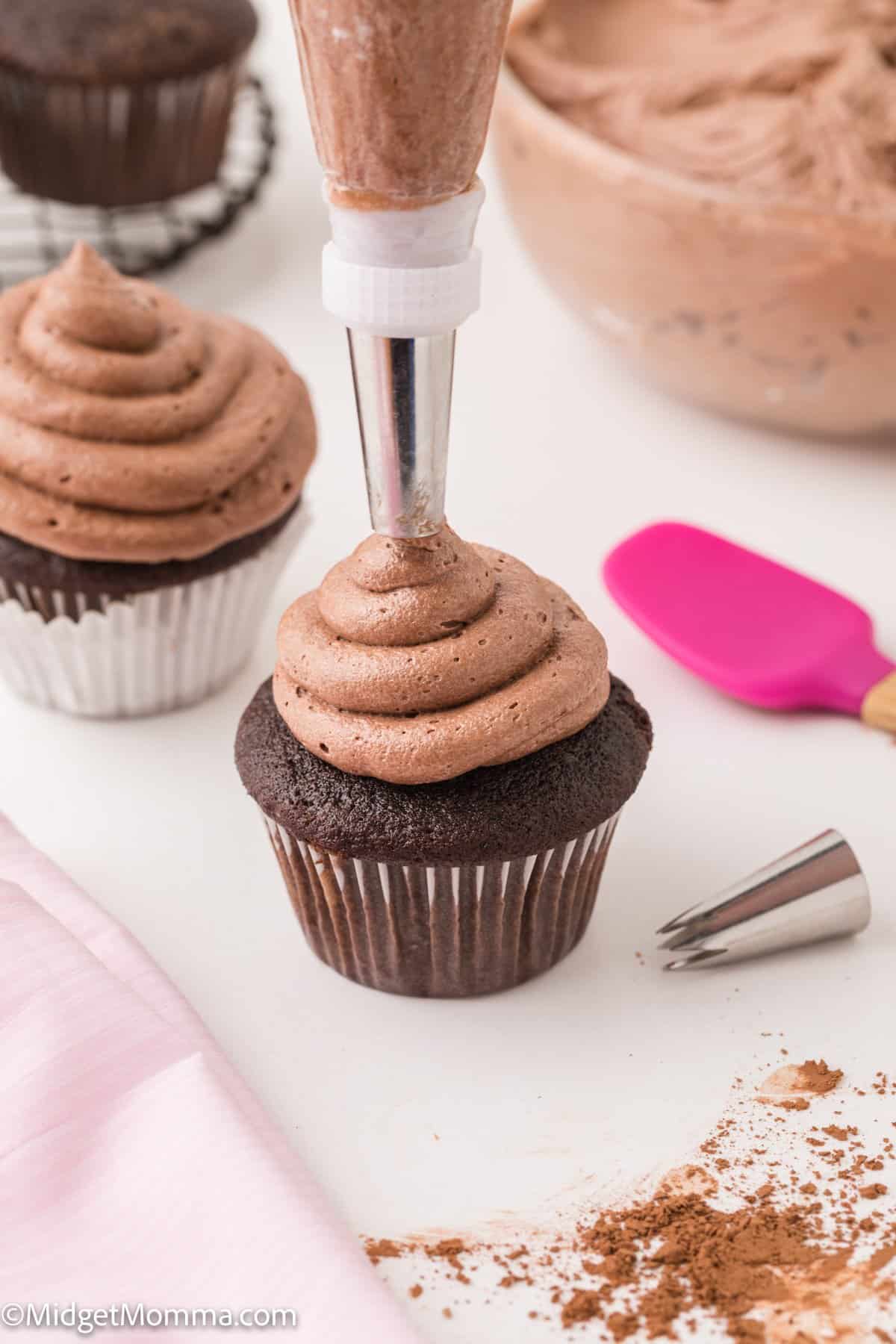 chocolate buttercream frosting being piped on top of a chocolate cupcake.