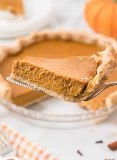 Side view of a slice of pumpkin pie on a pie serving utensil