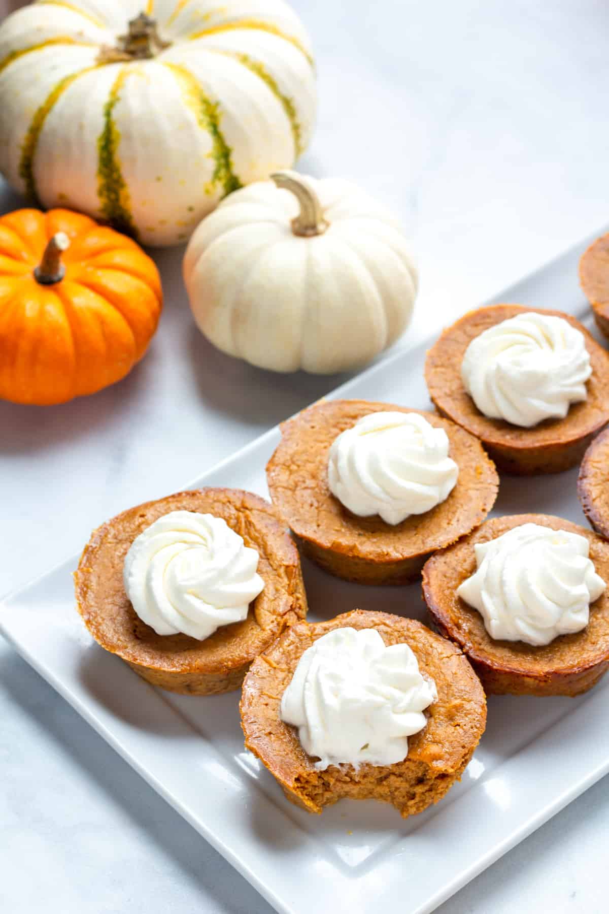 mini Pumpkin pies with whipped cream on a white plate.