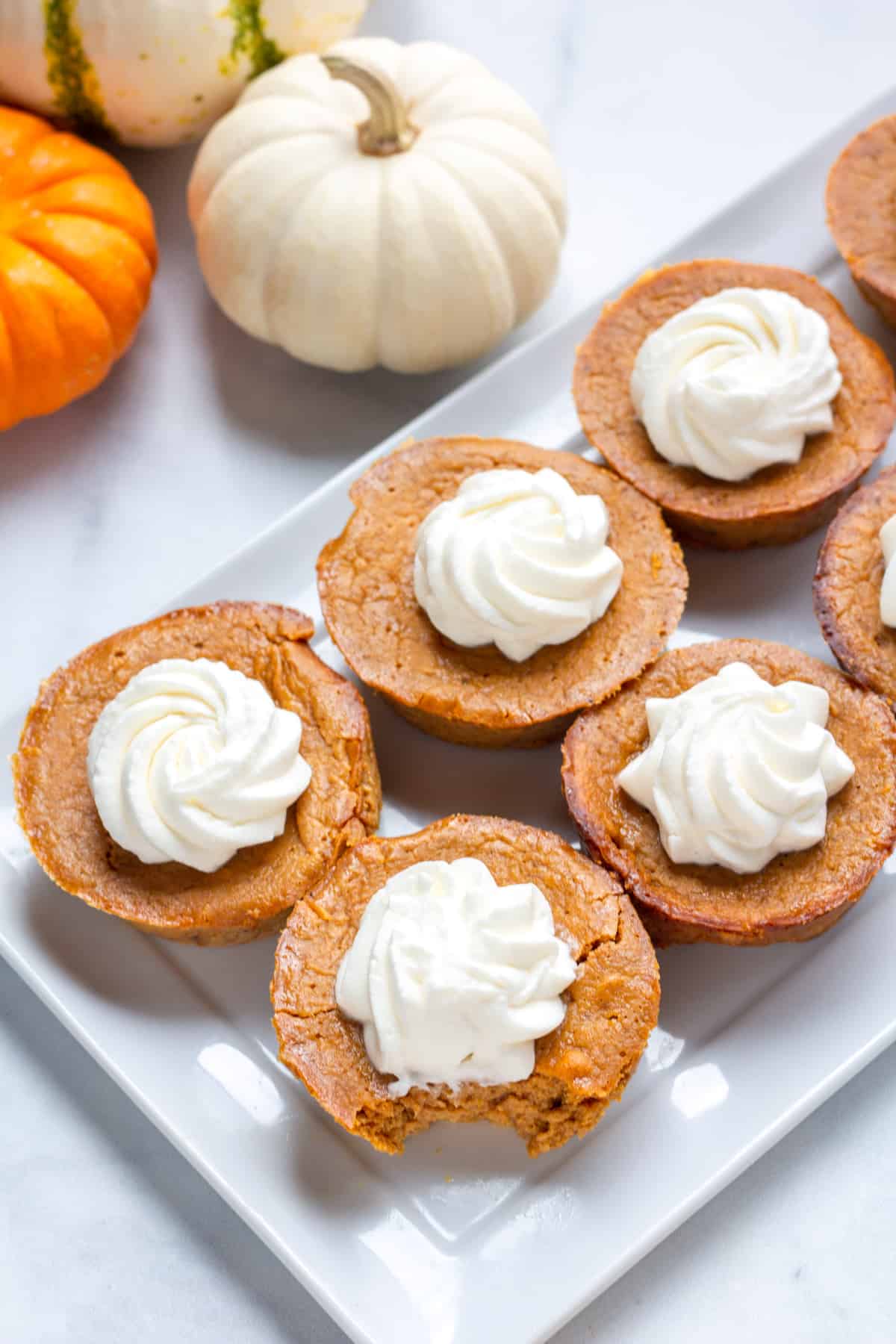 Pumpkin pie with no crust with whipped cream on a white plate.