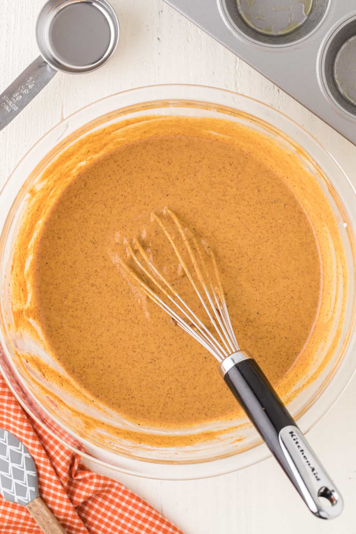 Pumpkin pie filling mixture in a bowl with a whisk.