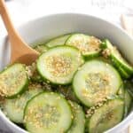 Asian Cucumber Salad in a white bowl with a serving spoon