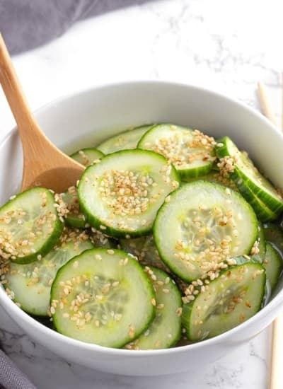 Asian Cucumber Salad in a white bowl with a serving spoon