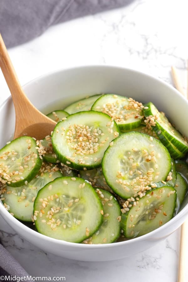 Asian Cucumber Salad in a white bowl with a serving spoon