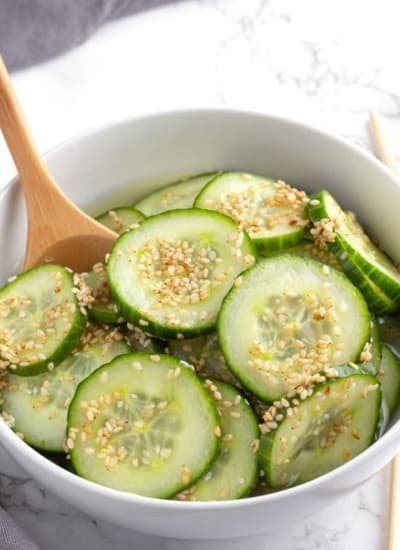 Asian Cucumber Salad in a white bowl with a serving spoon