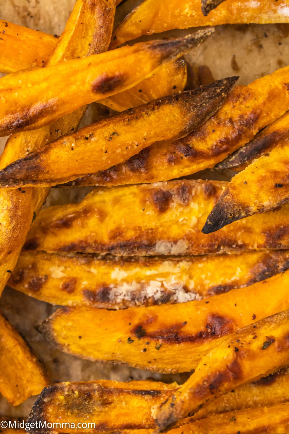 Close-up of seasoned, roasted sweet potato wedges on a baking sheet.