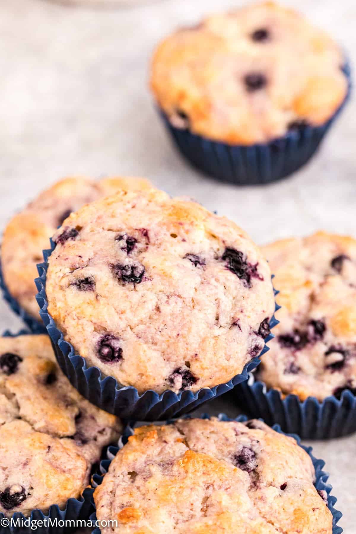 stack of blueberry muffins on the counter in muffin liners