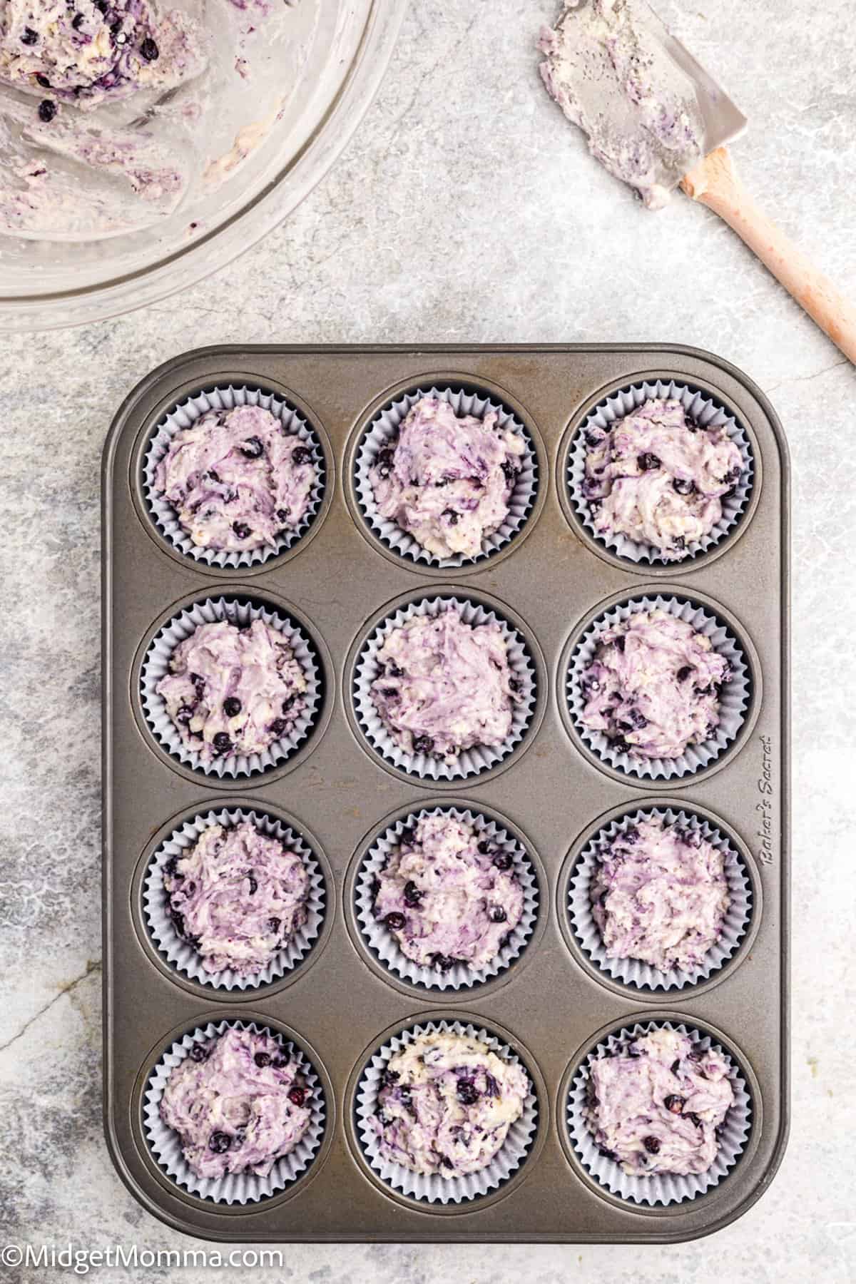 muffin tin filled with blueberry muffin batter