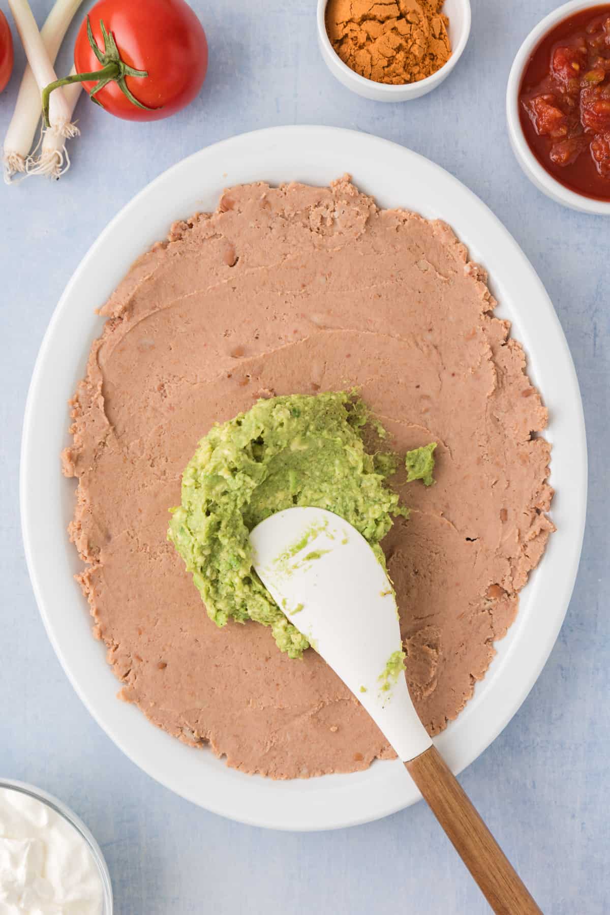 mashed avocado spread on top of refried beans for 7 layer dip