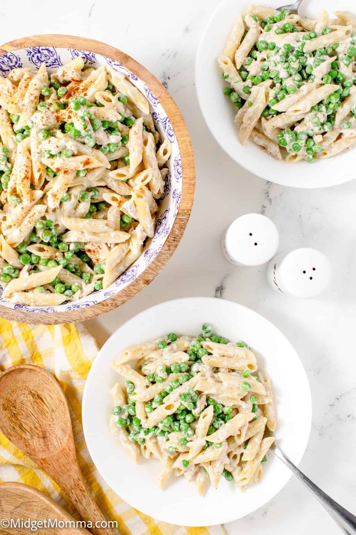 overhead photo of tuna pasta salad in a serving bowl with 2 bowls filled with pasta salad