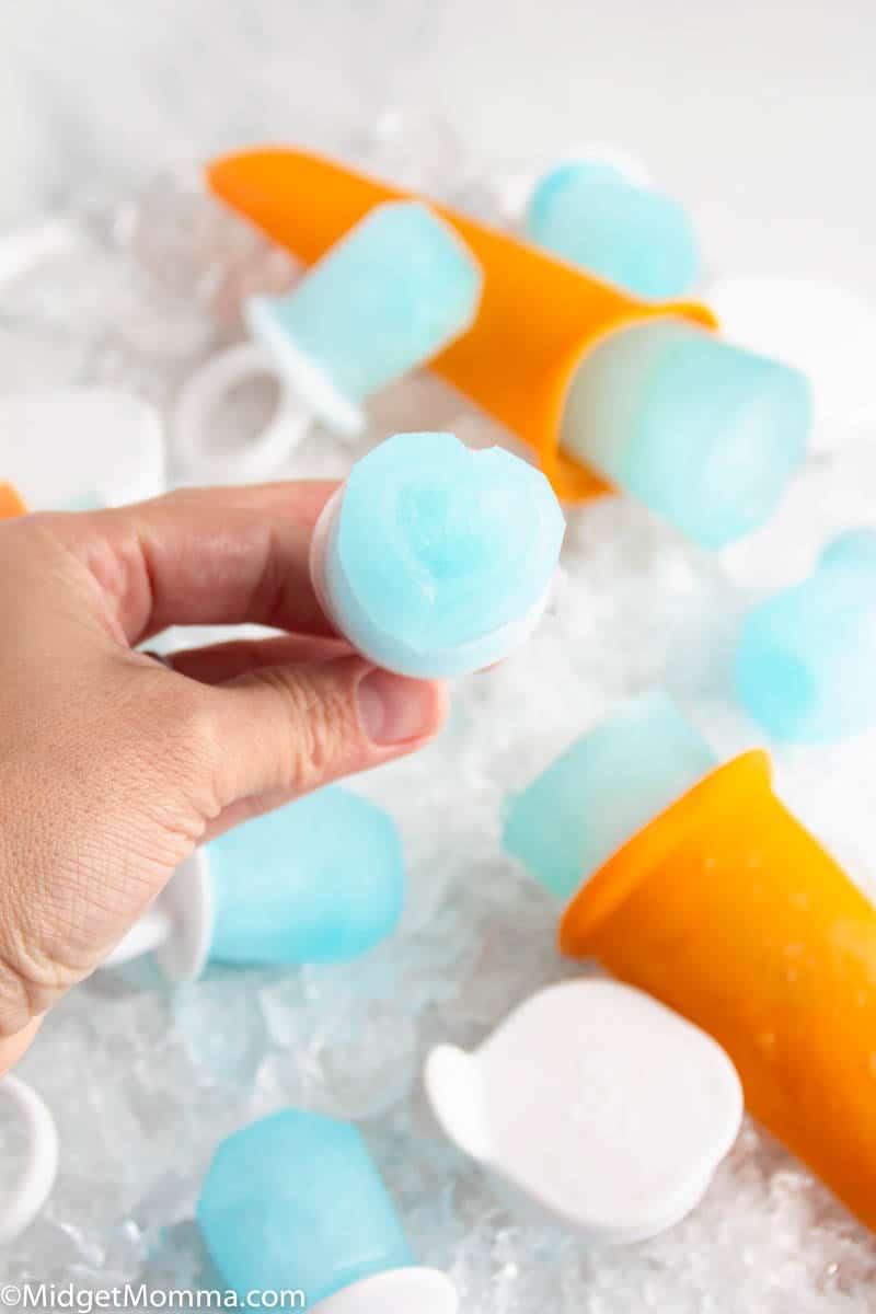 child's hand holding a homemade pedialyte popsicle with other pedialyte popsicles in the background