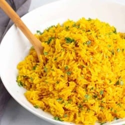 Instant Pot Turmeric Rice in a white bowl with a wooden spoon