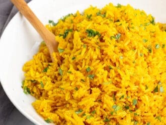 Instant Pot Turmeric Rice in a white bowl with a wooden spoon