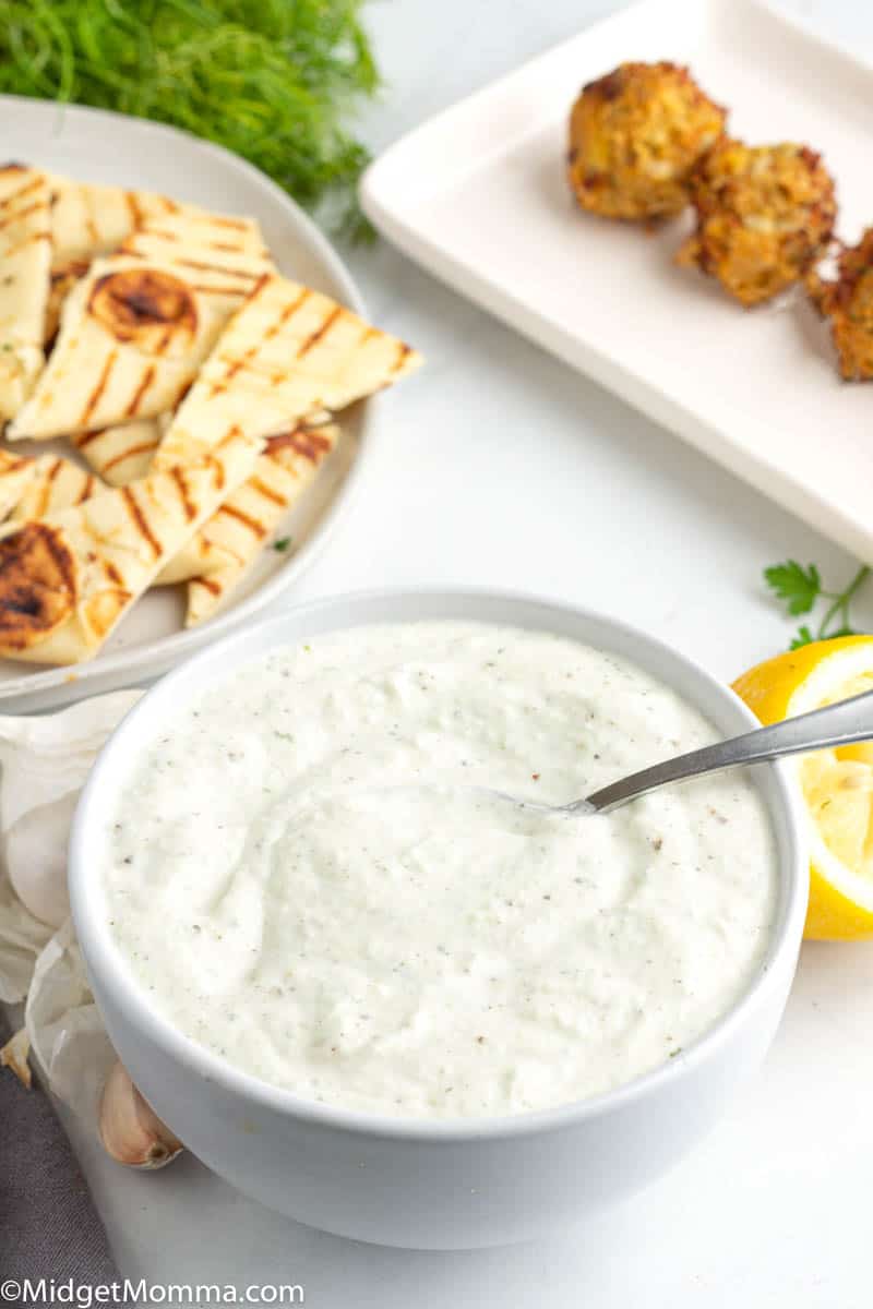 Tzatziki Sauce Recipe in a white bowl with a spoon and pita bread