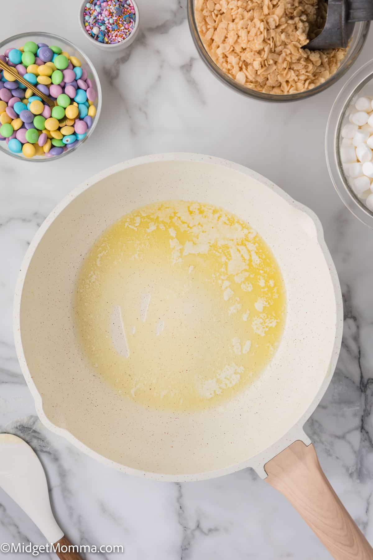 Melted butter in a saucepan with ingredients for baking displayed in bowls around it.