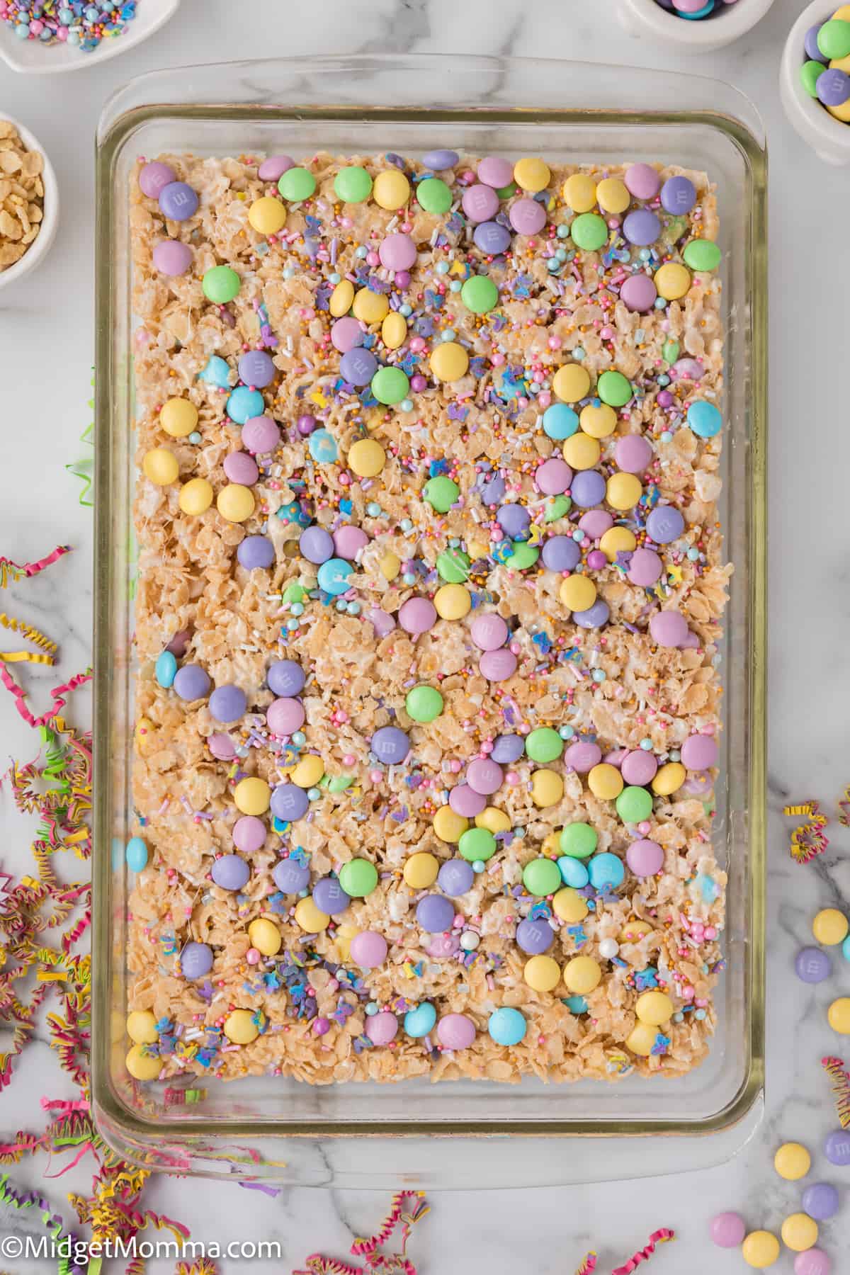 Colorful candy-topped rice cereal treats in a baking tray.