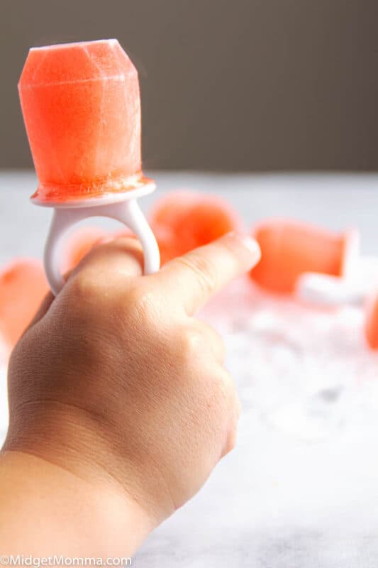 Raspberry Pedialyte Pop being held by a childs hand