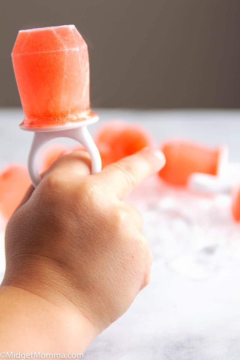 Raspberry Pedialyte Pop being held by a childs hand